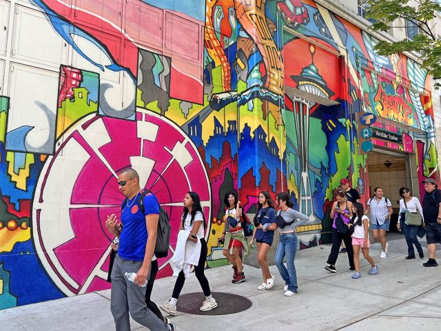 People walking in front of mural